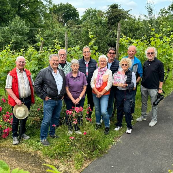 Mitglieder der Gruppe stehen mit Bürgermeister Ulf Hürtgen vor dem Weinberg, den sie betreuen.