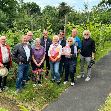 Mitglieder der Gruppe stehen mit Bürgermeister Ulf Hürtgen vor dem Weinberg, den sie betreuen.