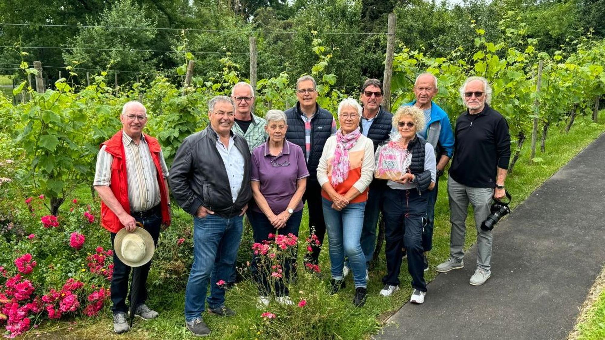 Mitglieder der Gruppe stehen mit Bürgermeister Ulf Hürtgen vor dem Weinberg, den sie betreuen.