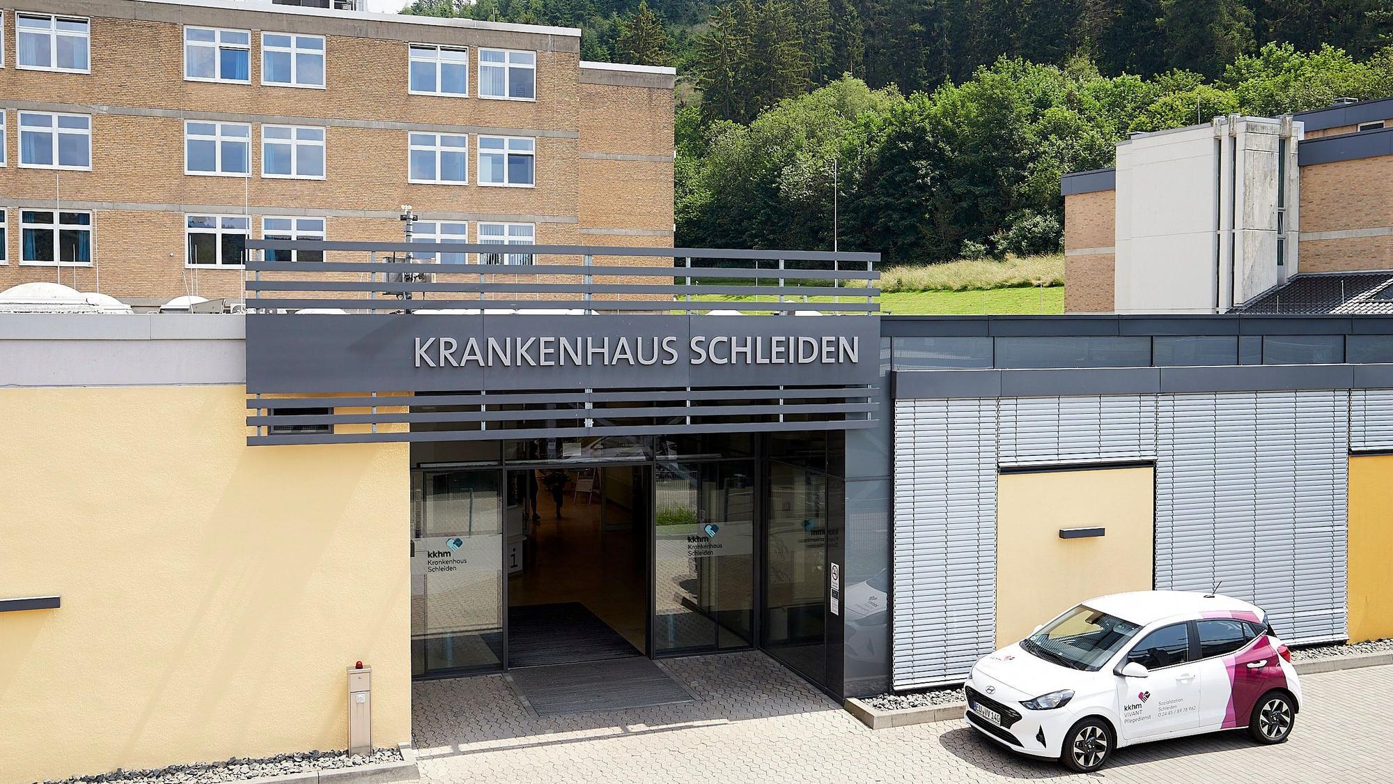 Das Bild zeigt den Haupteingang des Krankenhauses Schleiden, davor parkt ein Auto.
