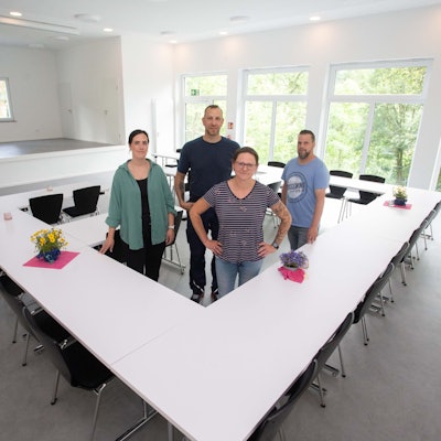 Vier Personen in der Mitte eines hellen Saals.