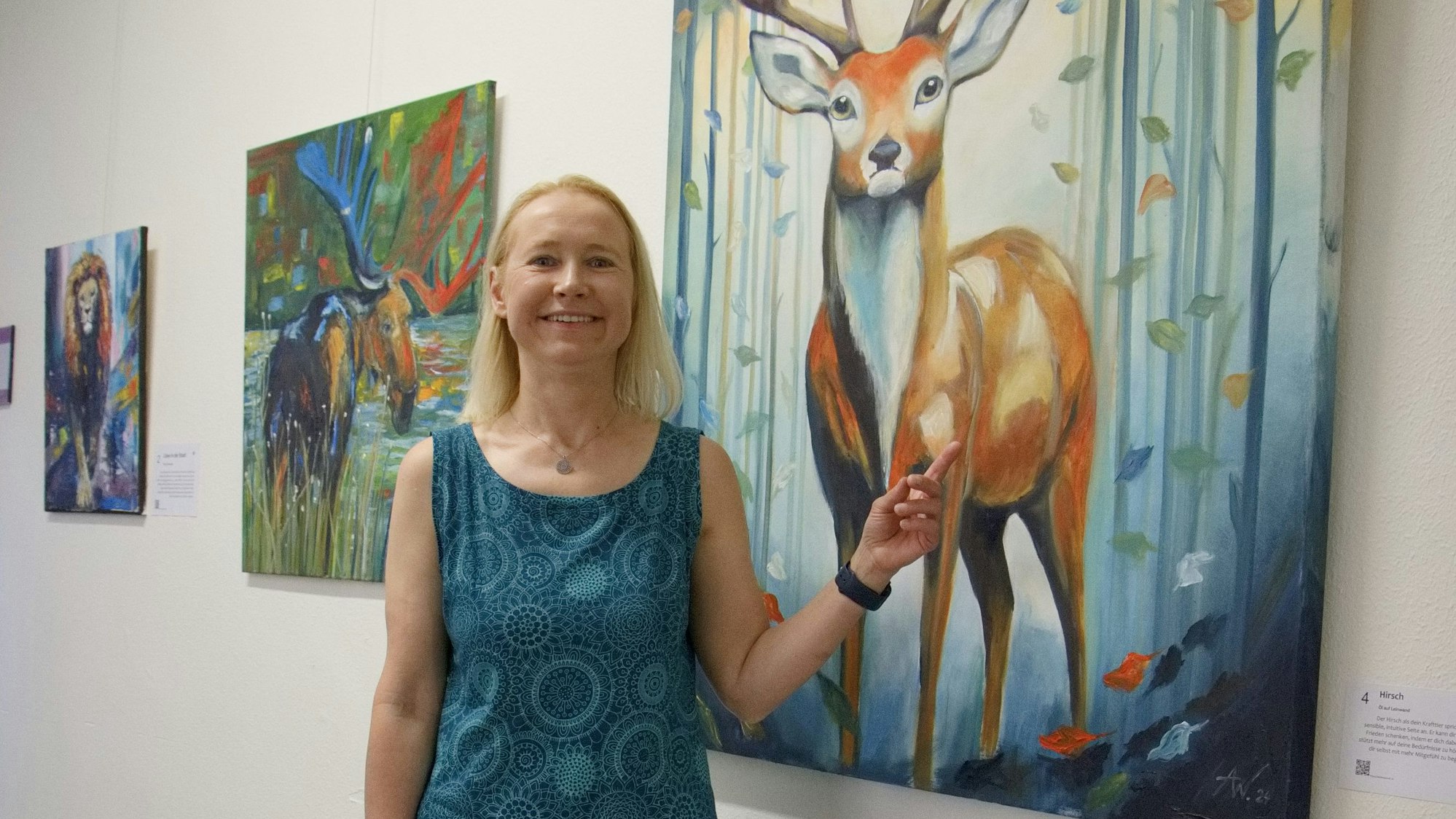 Die Malerin Anja Weitz vor einem ihrer Bilder, das einen Hirsch zeigt.