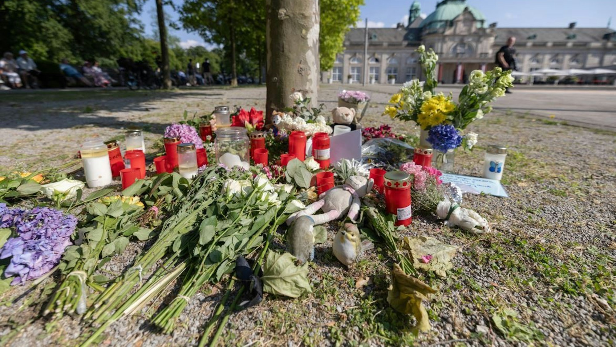 Blumen, Kerzen und handgeschriebene Trauerbekundungen stehen an einem Baum im Kurpark Bad Oeynhausen. Nach der tödlichen Attacke im Kurpark hatte die Polizei einen 18-jährigen Tatverdächtigen festgenommen.