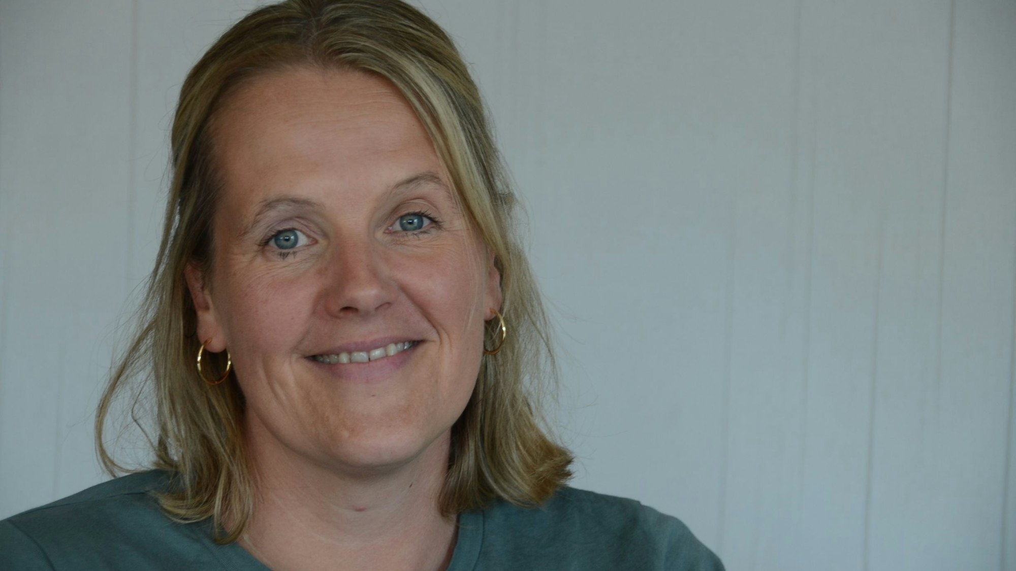 Eine blonde Frau in einem grünen T-Shirt.