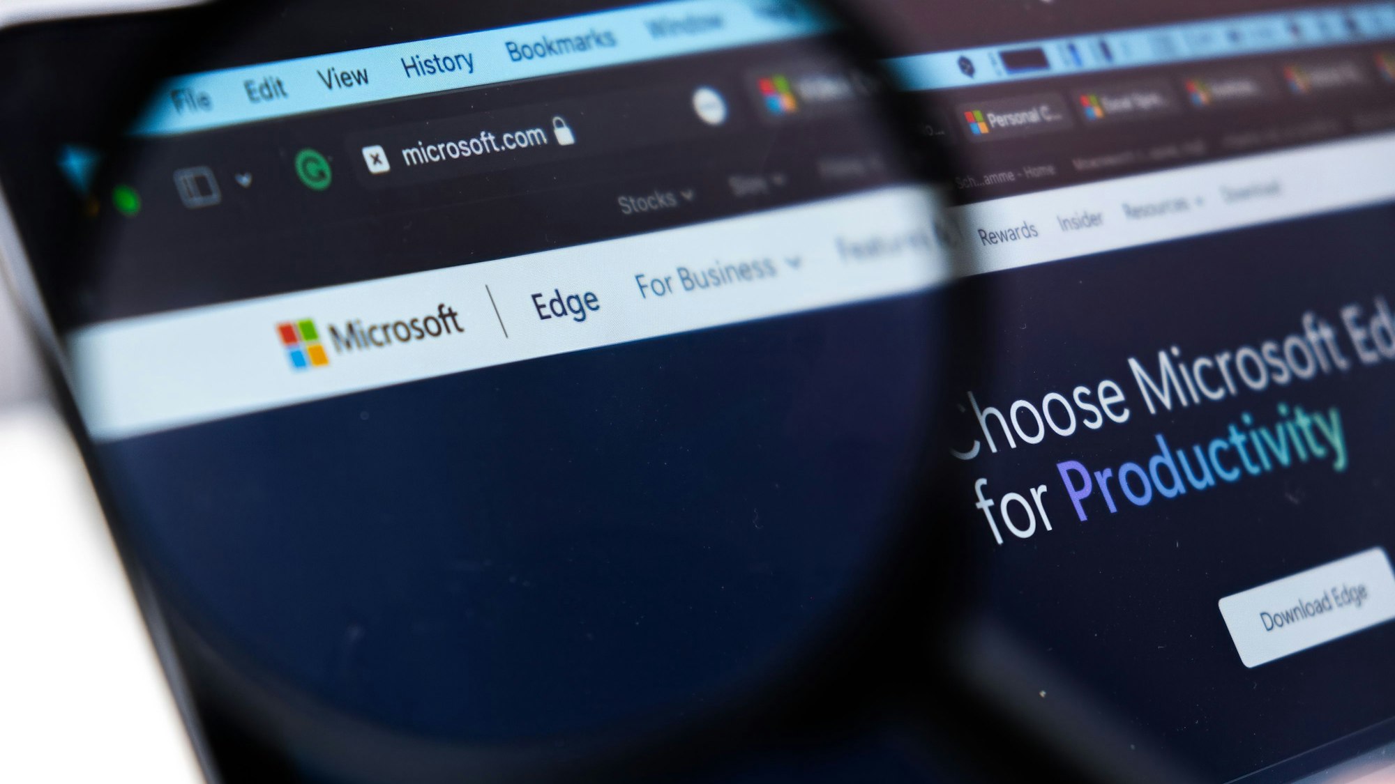 Durch eine Lupe sieht man einen Teil der Microsoft-Website im Browser Microsoft Edge.
