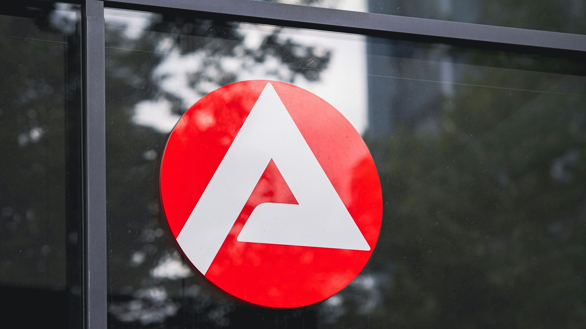 Das Bild zeigt das Symbol-A der Agentur für Arbeit, das auf einem Fenster angebracht ist.