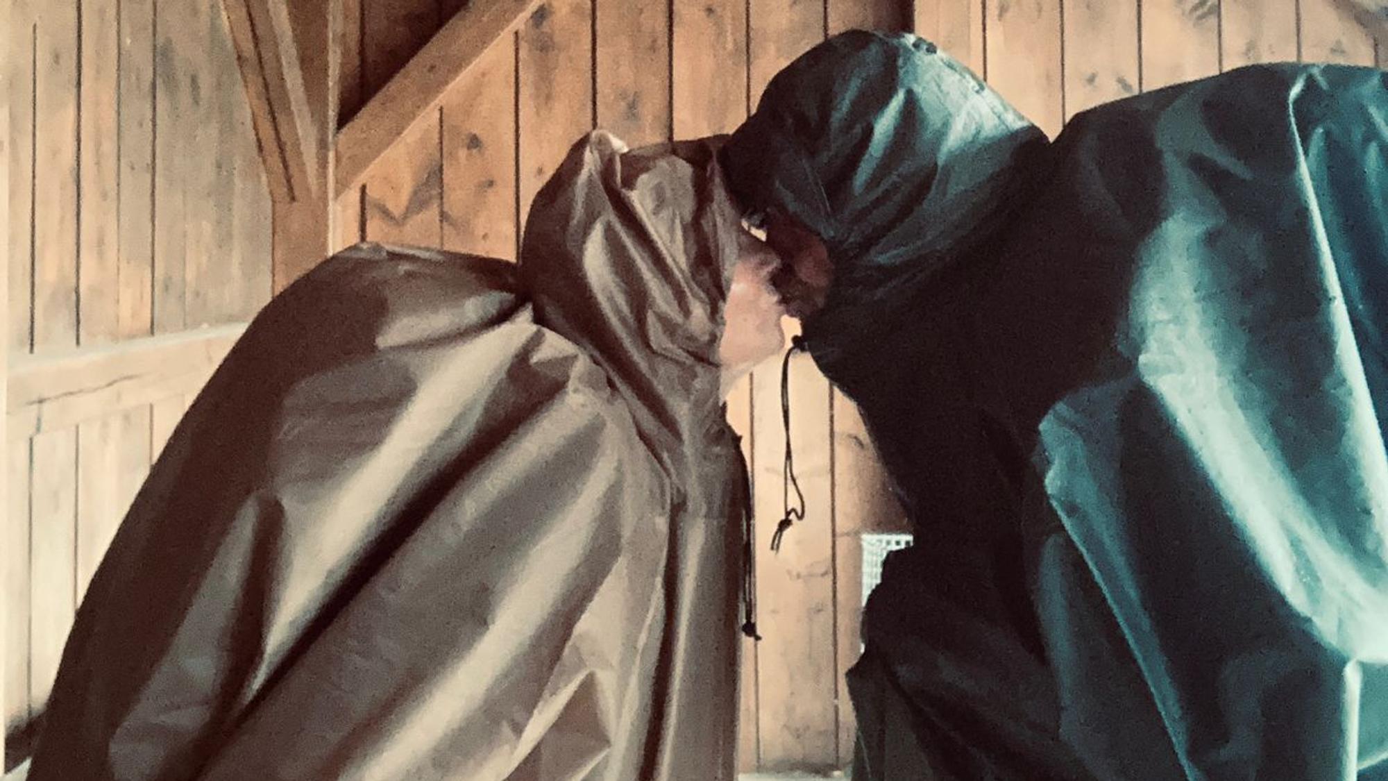 Bettina und Ralf Schaffrath tragen Regencapes und küssen sich.