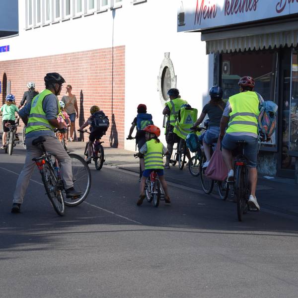 Erwachsene und Kinder sind in Warnwesten auf ihrem Fahrrad unterwegs.