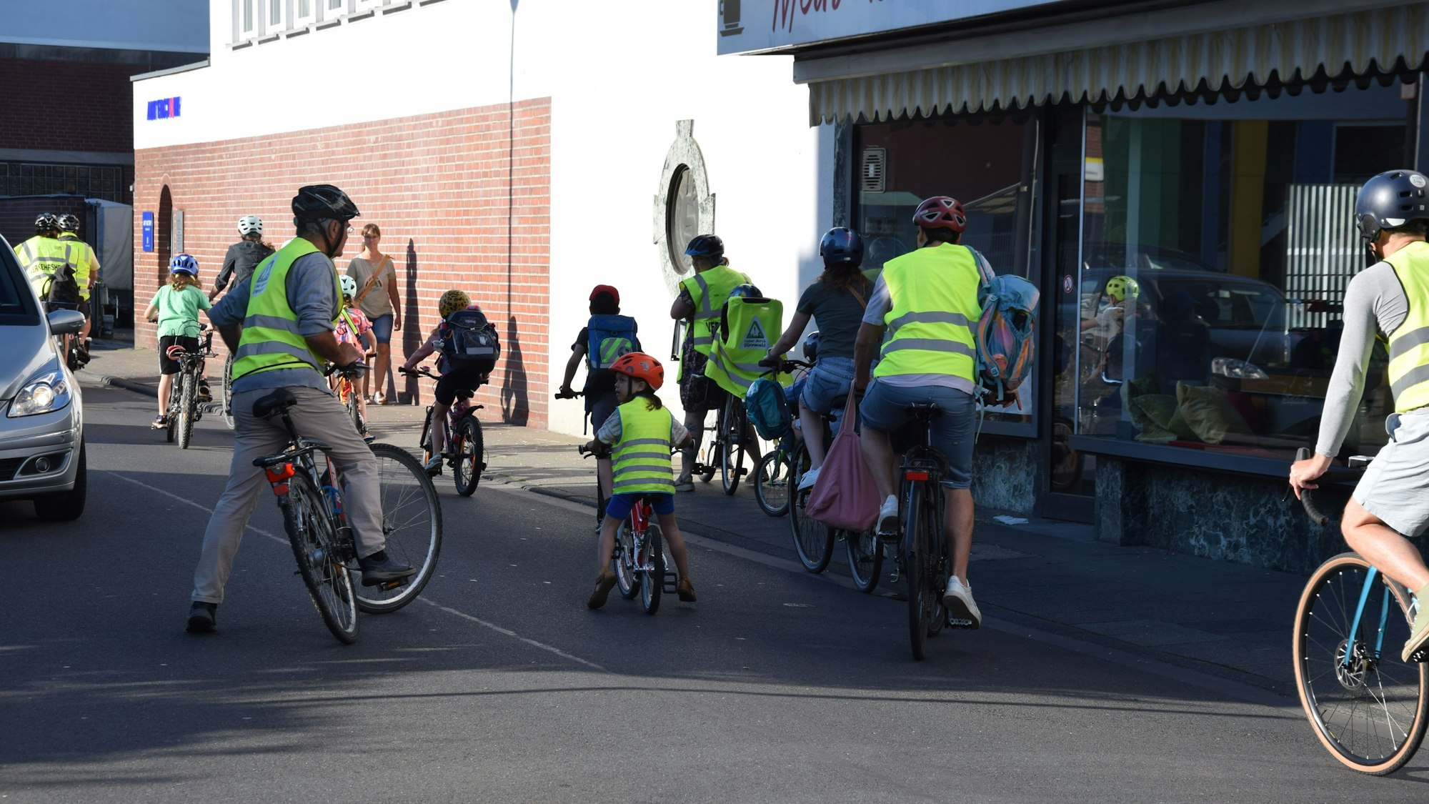 Erwachsene und Kinder sind in Warnwesten auf ihrem Fahrrad unterwegs.
