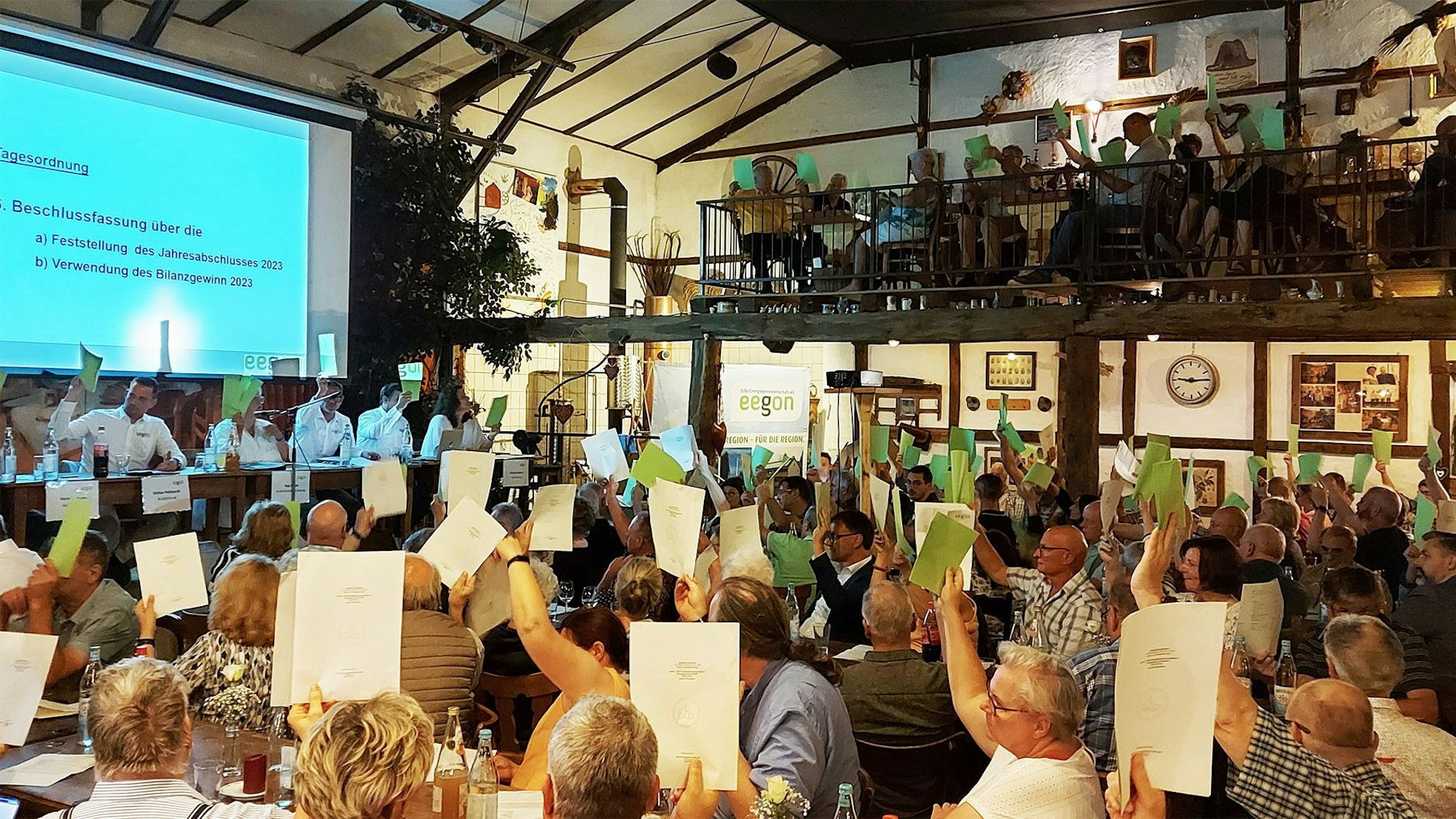 Mitglieder der Eegon bei der Hauptversammlung in Birgel. Zur Abstimmung halten viele Papierbögen in die Höhe.