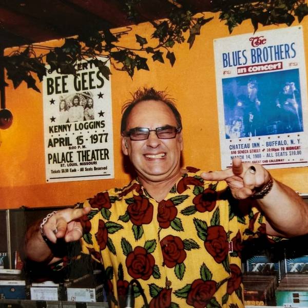 Ein Mann in buntem Hawaii-Hemd steht hinter einem DJ-Pult.