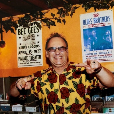 Ein Mann in buntem Hawaii-Hemd steht hinter einem DJ-Pult.