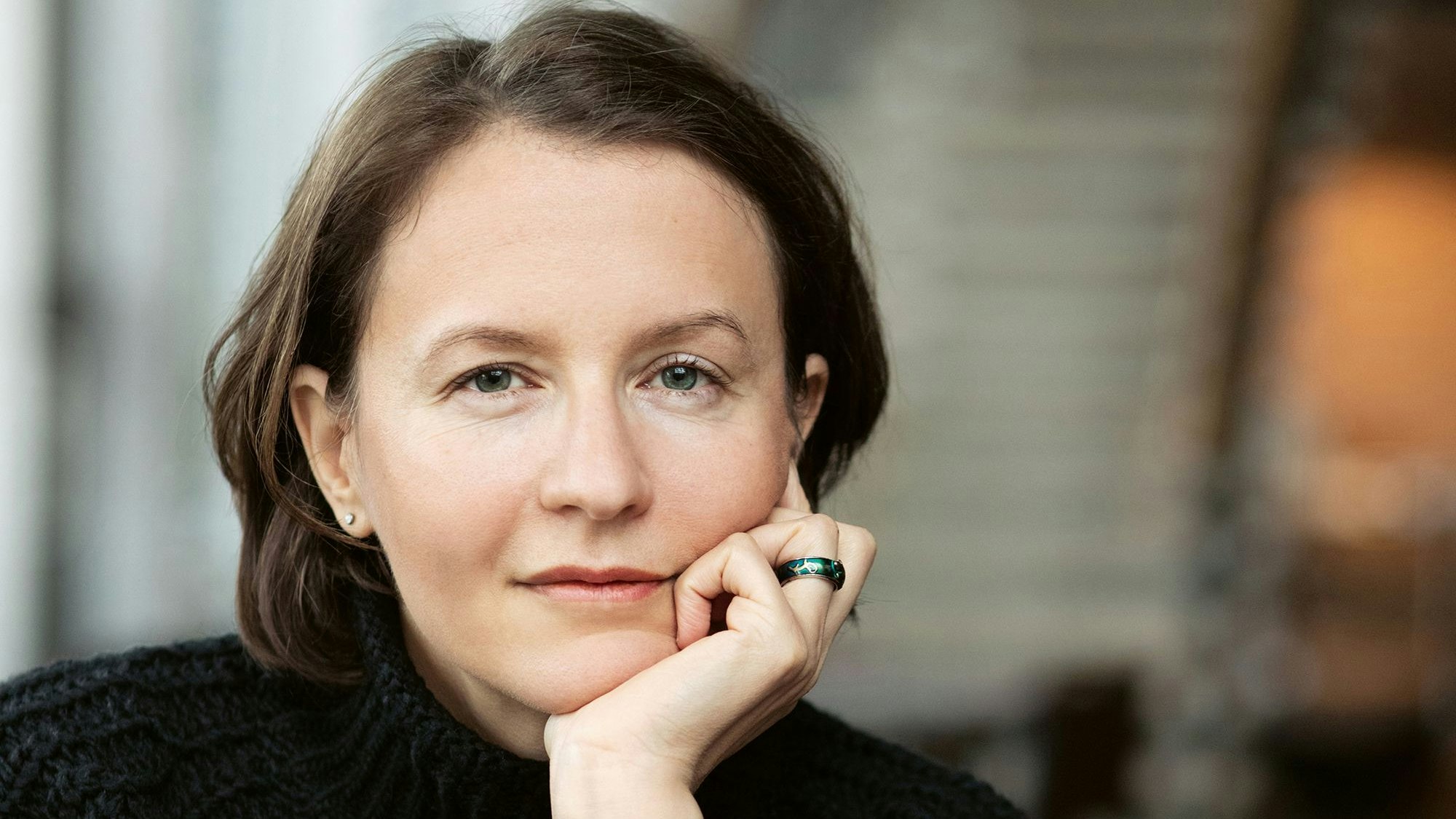 Alina Bronsky schaut in die Kamera, ihr Gesicht auf dem linken Arm aufgestützt.