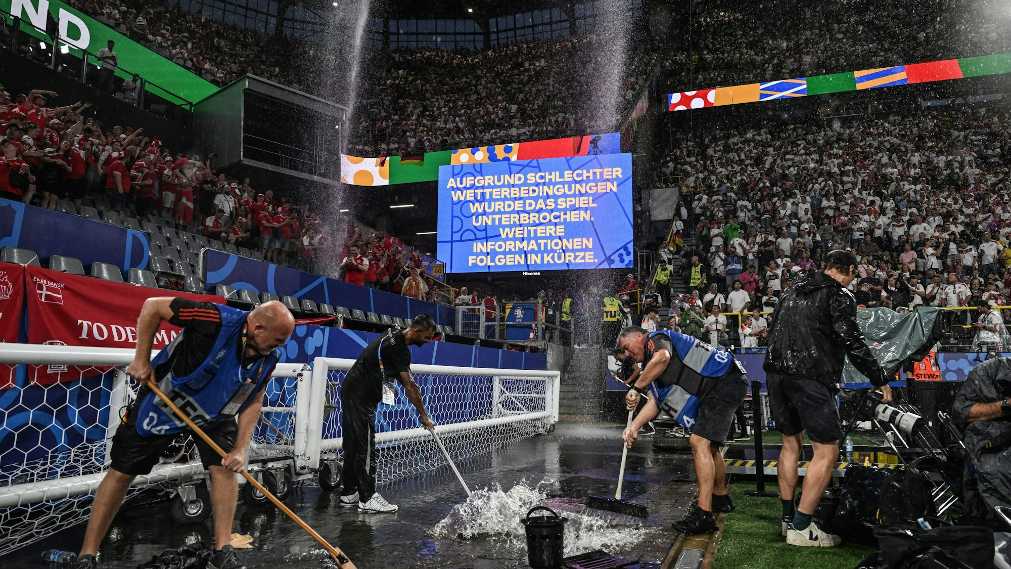 Saubermachen in Dortmund: Eine Anzeigentafel informiert über eine Spielunterbrechung wegen schlechten Wetters während des EM-Sipels zwischen Deutshcland und Dänemark.