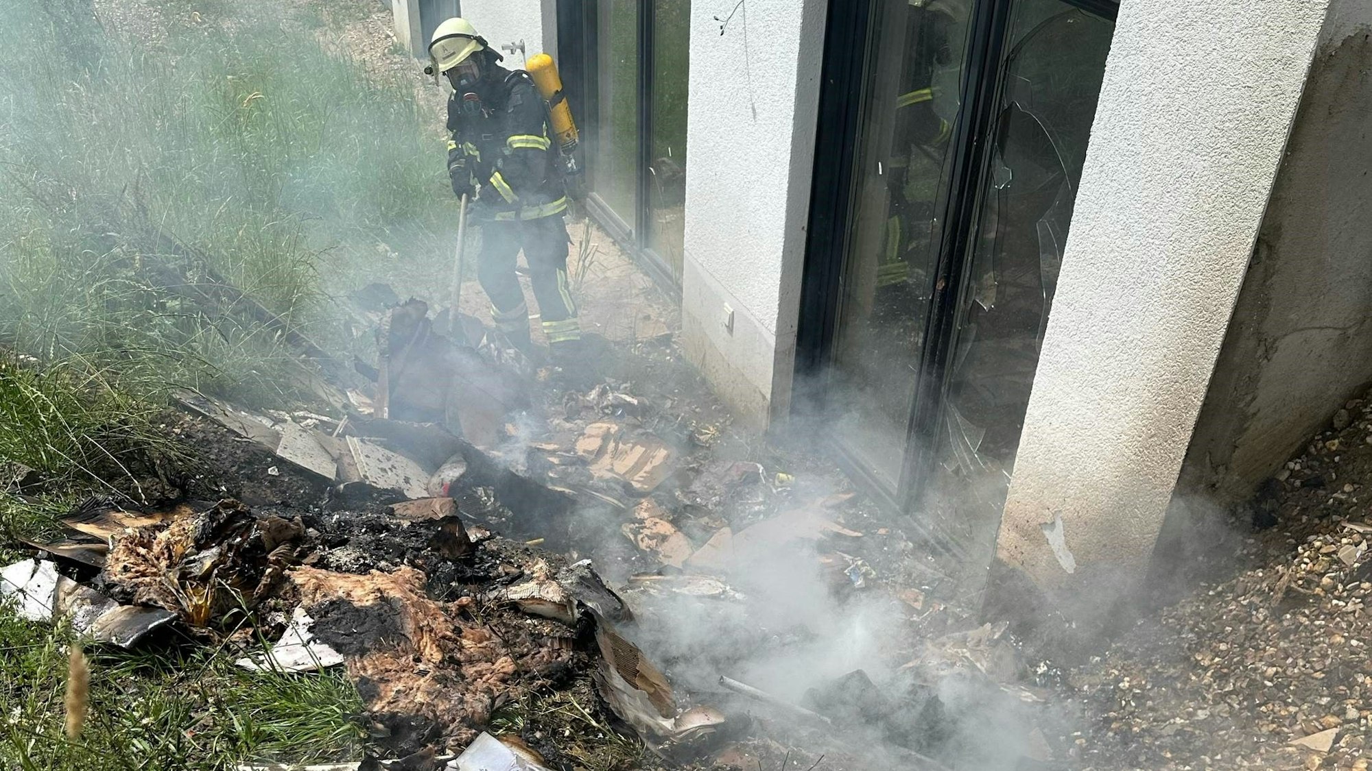 Ein Feuerwehrmann steht vor einem qualmenden Haufen.