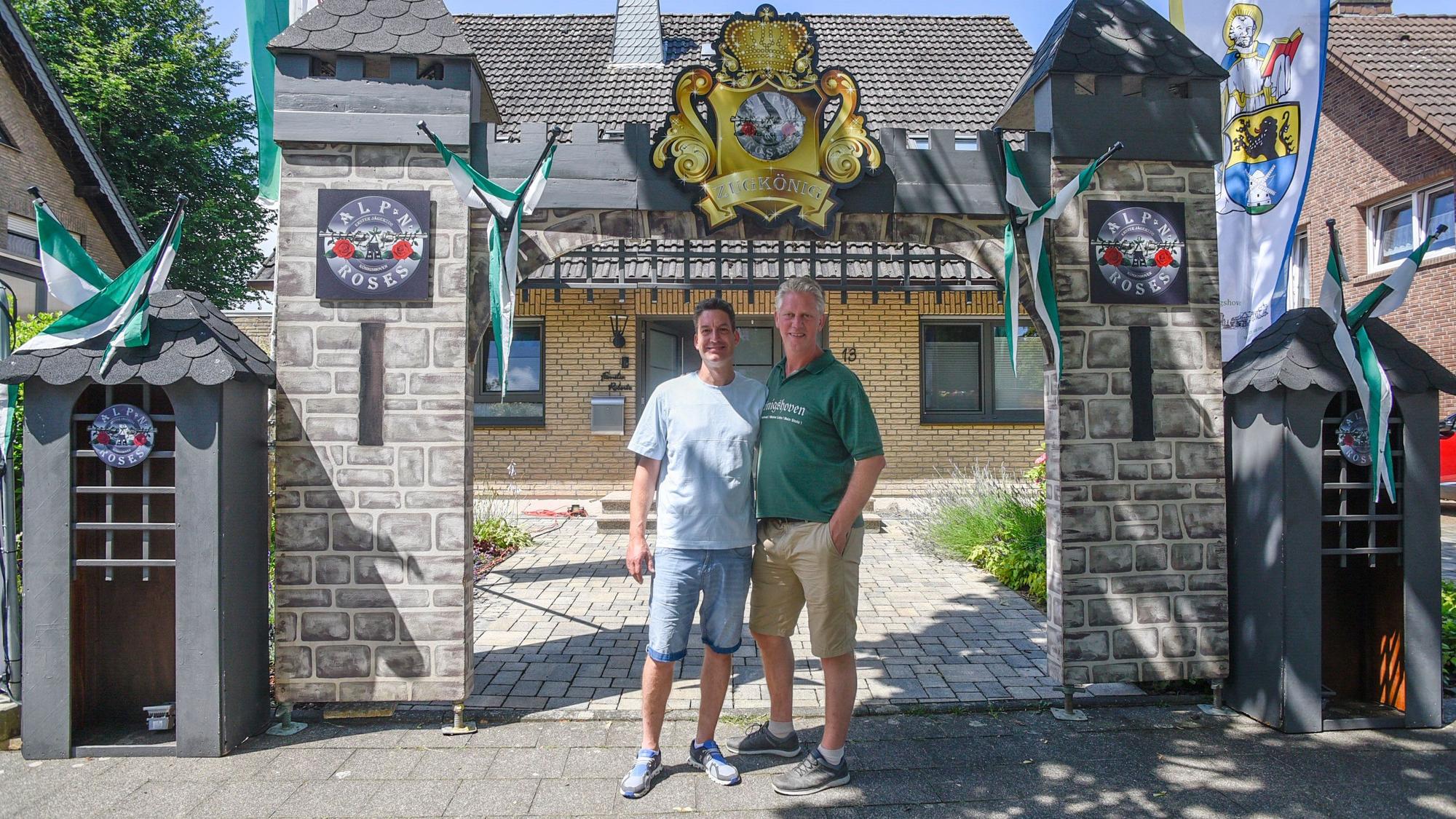 Auf dem Bild sind zwei Männer vor einer Torburg zu sehen.