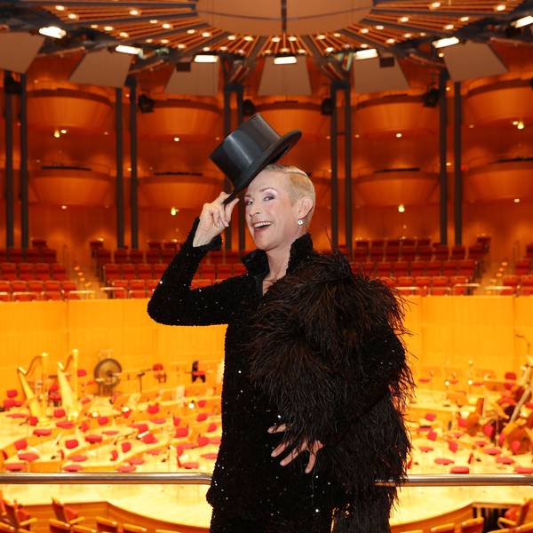 Tim Fischer auf Stippvisite in Köln in der Philharmonie.
Der Chansonnier trägt ein schwarzes Glitzerjackett, eine schwarze Federboa und grüßt mit einem Zylinderhut.