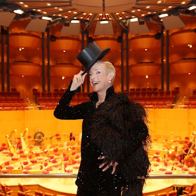 Tim Fischer auf Stippvisite in Köln in der Philharmonie.
Der Chansonnier trägt ein schwarzes Glitzerjackett, eine schwarze Federboa und grüßt mit einem Zylinderhut.