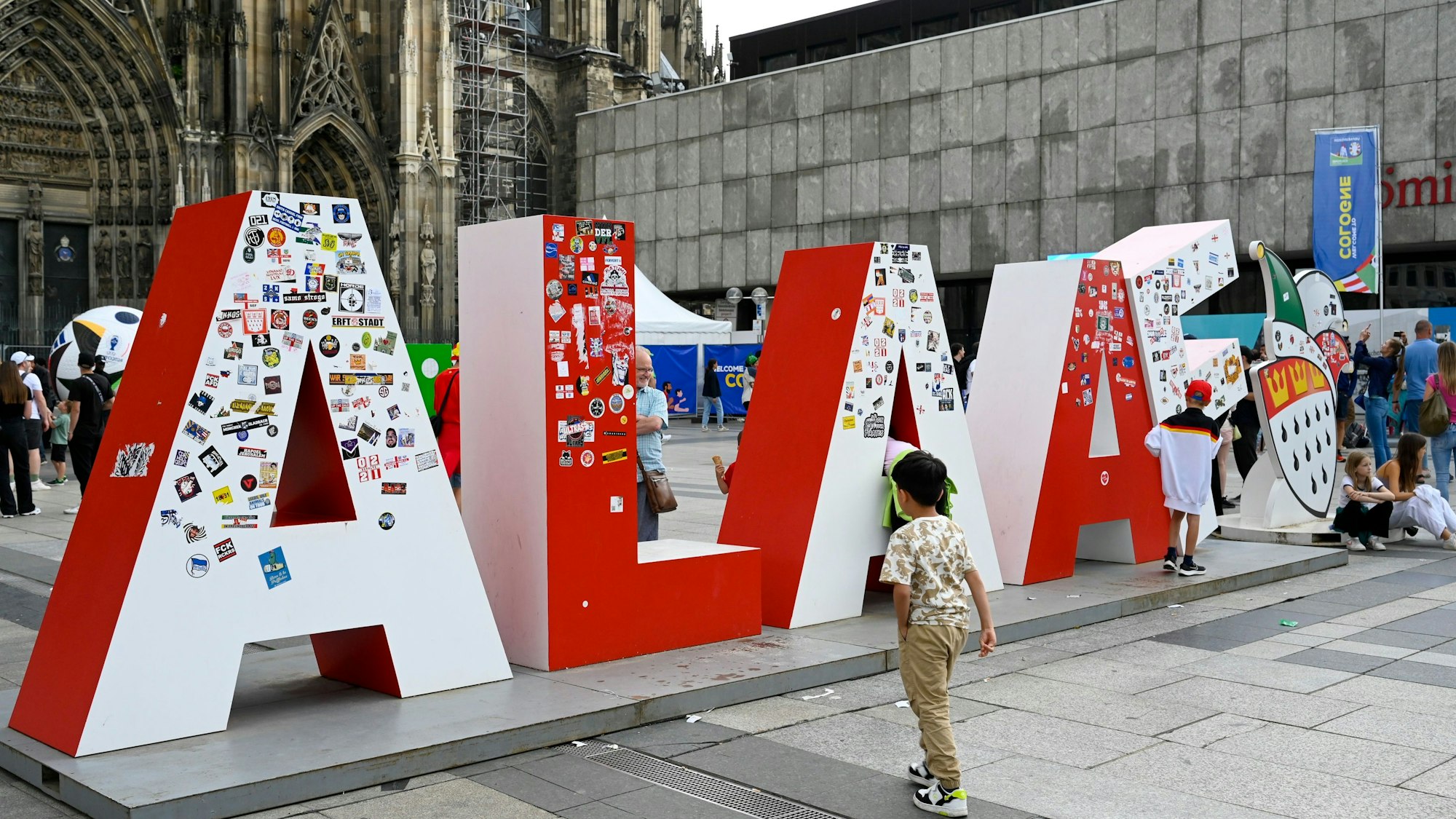 Mit Aufklebern verschandelt auf dem Roncalliplatz: der tonnenschwere Schriftzug des Festkomitees Kölner Karneval