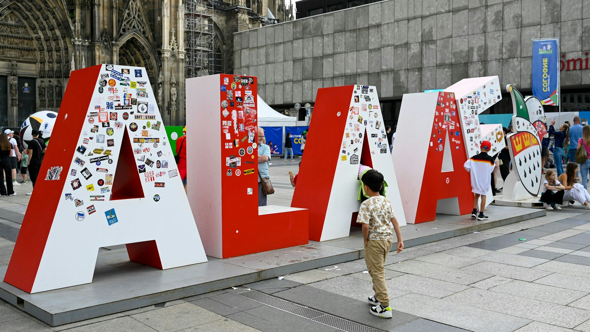 Skulptur mit den Buchstaben "Alaaf" steht vor dem Dom und ist voller Aufkleber.