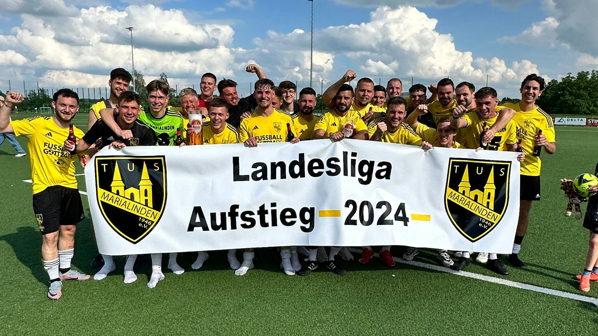 Das Team feiert mit einem Banner den Aufstieg