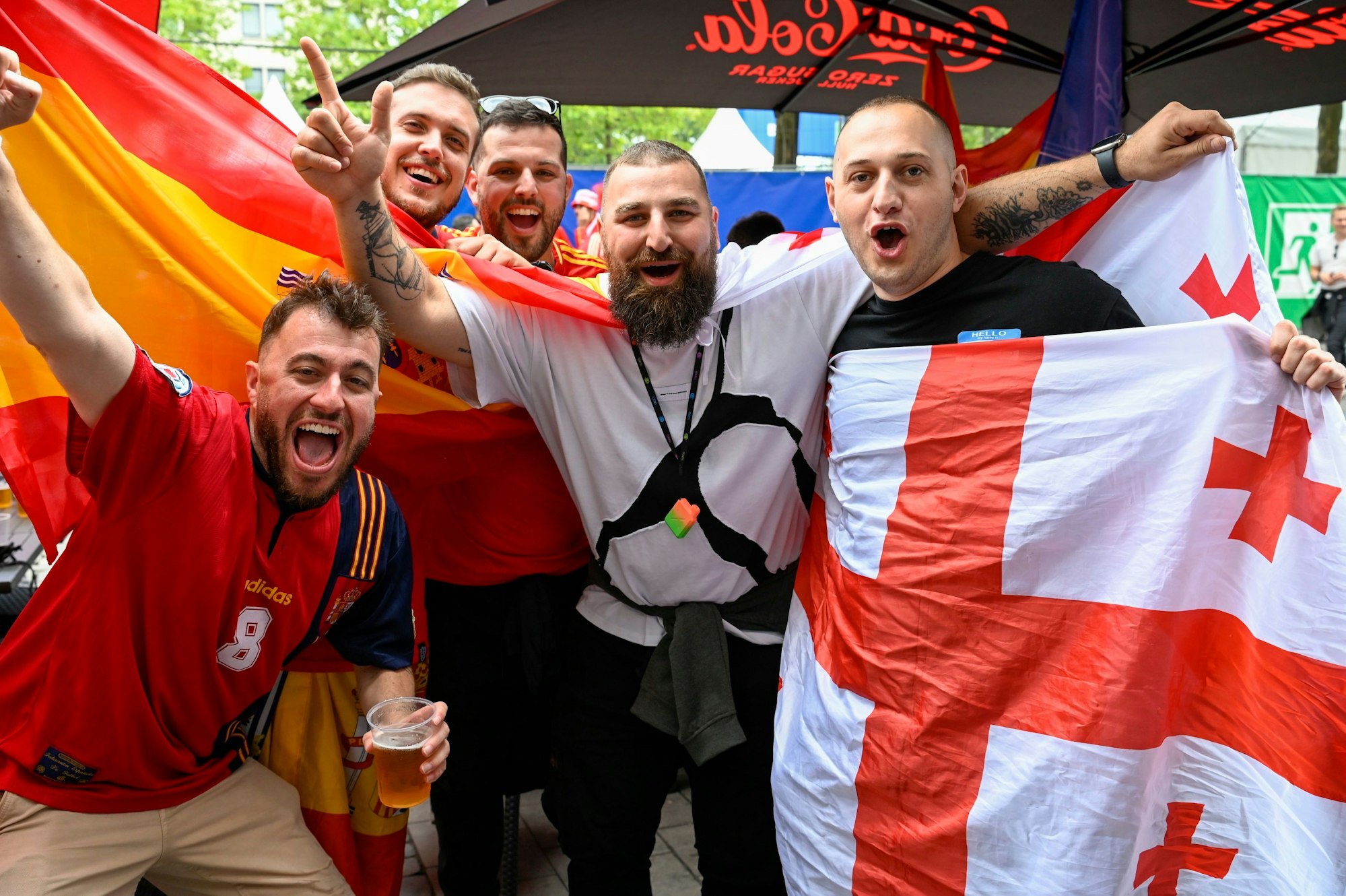 Männer mit spanischer und georgischer Flagge jubeln in die Kamera.