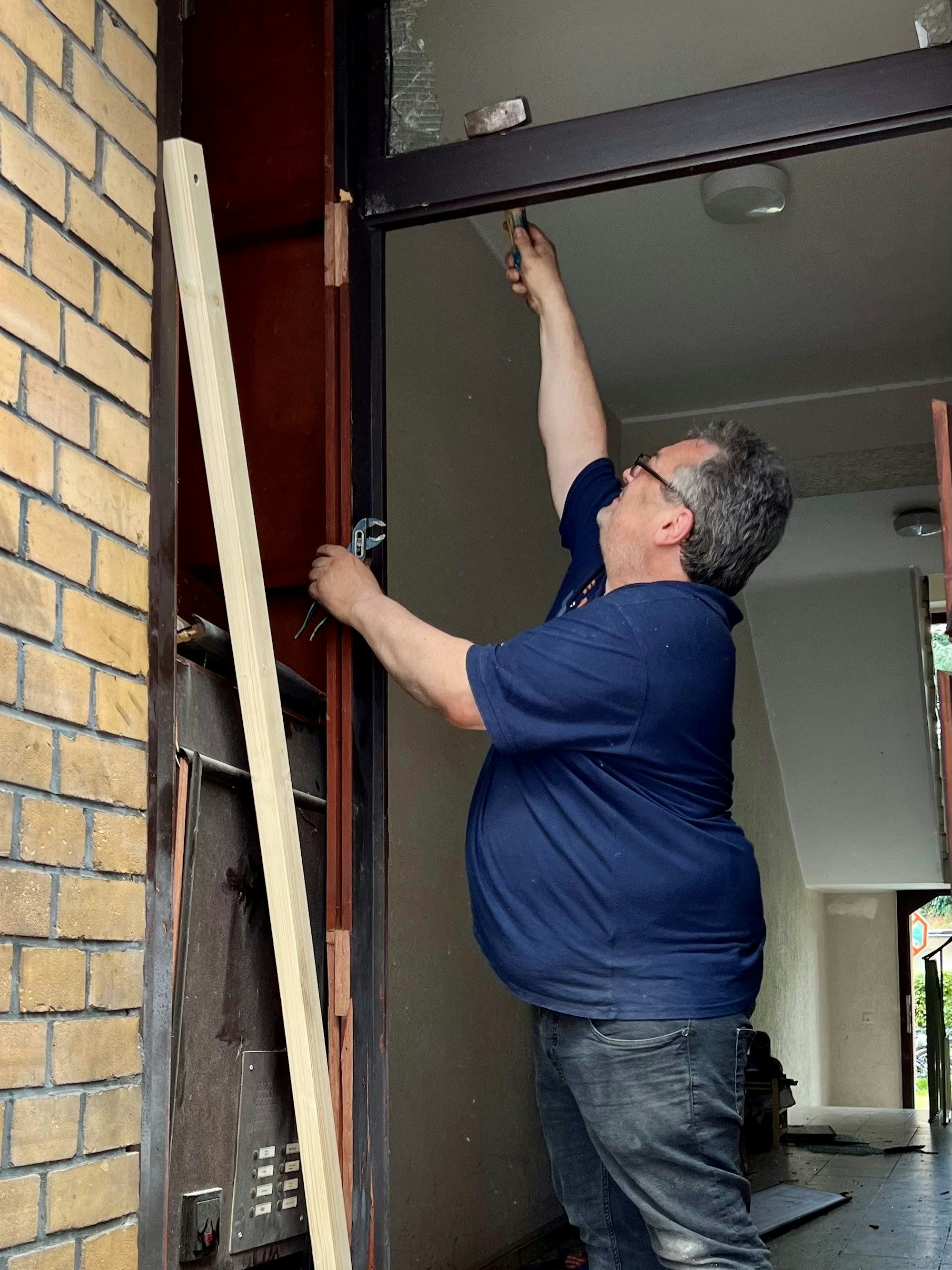 Udo Roth schlägt mit einem Hammer Glasreste aus dem Türrahmen.