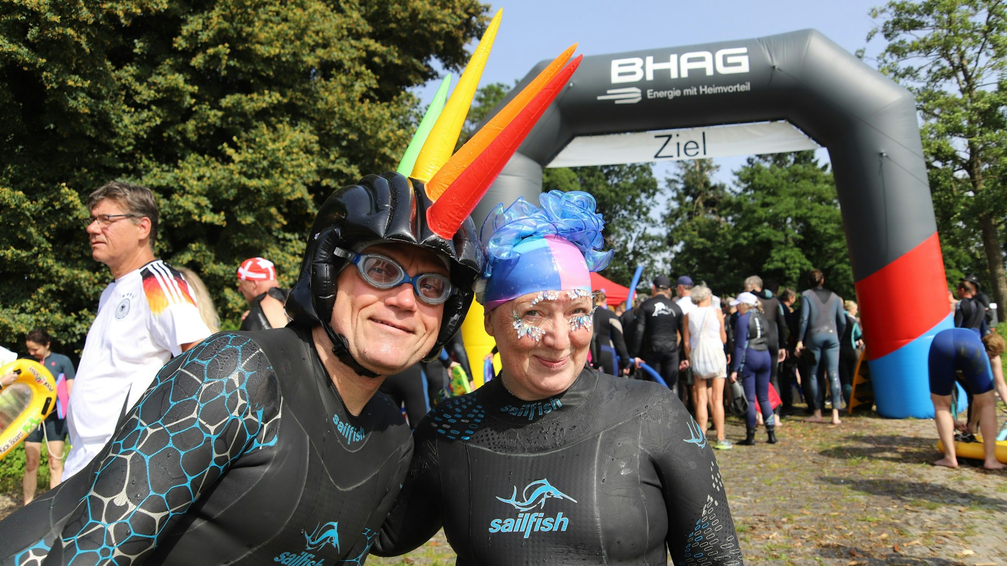 Ein Mann und eine Frau in Neoprenanzügen und mit bunten Kopfbedeckungen.