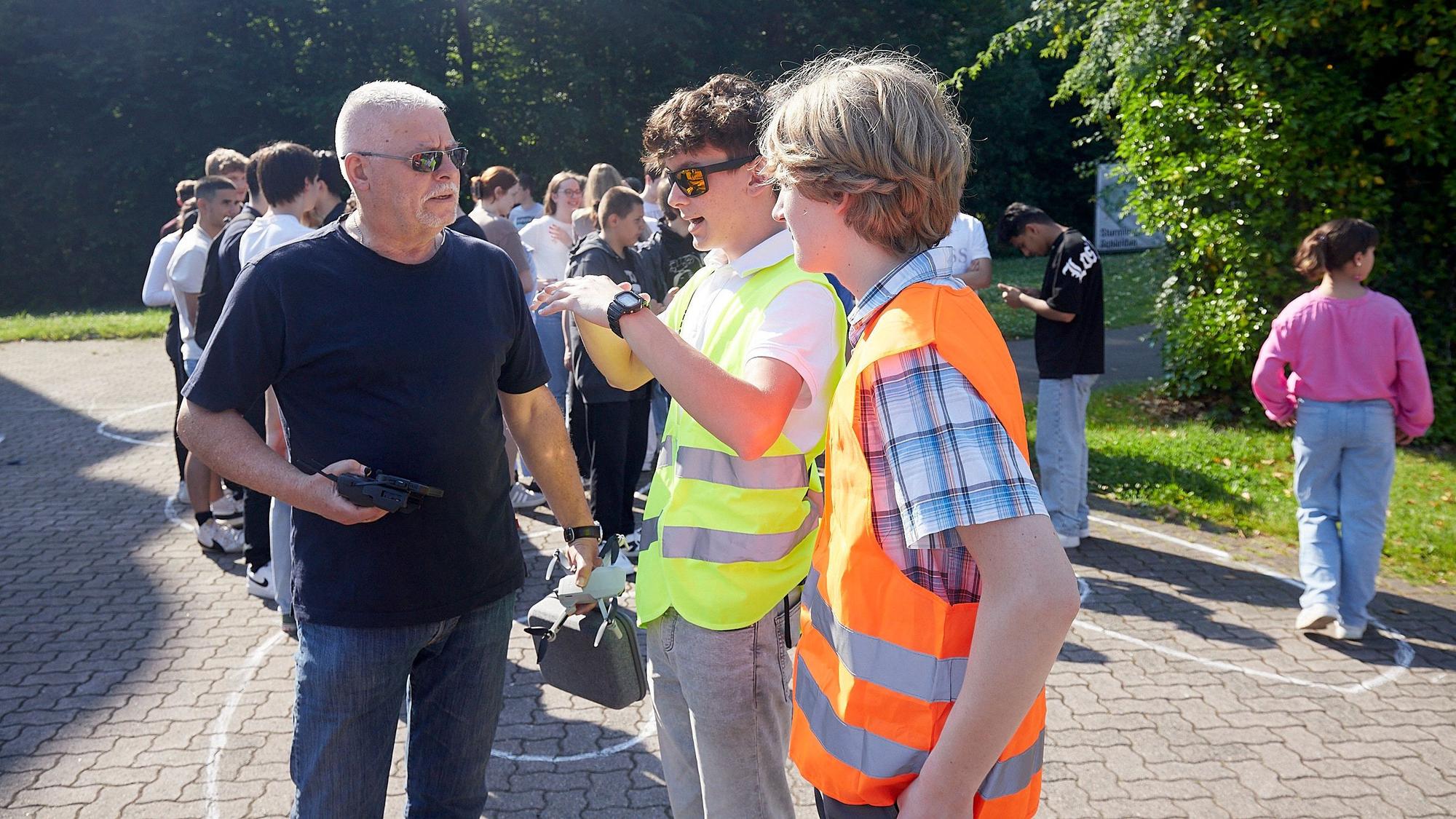 Die Schülersprecher Christian Baran und Hlynur Jakob Limbeck im Gespräch mit Fotograf Horst Fehse. Die beiden Jugendlichen tragen signalfarbene Warnwesten.