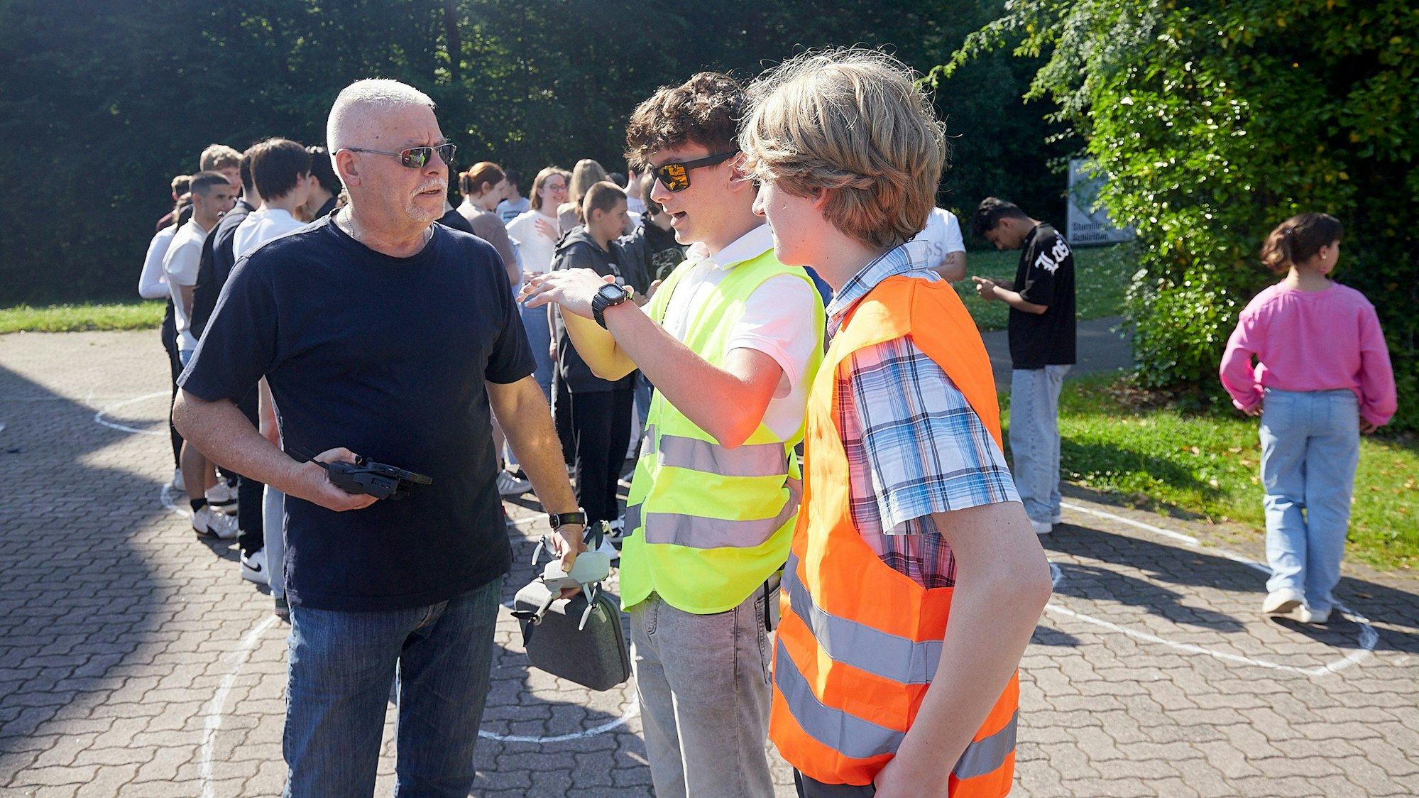 Die Schülersprecher Christian Baran und Hlynur Jakob Limbeck im Gespräch mit Fotograf Horst Fehse. Die beiden Jugendlichen tragen signalfarbene Warnwesten.