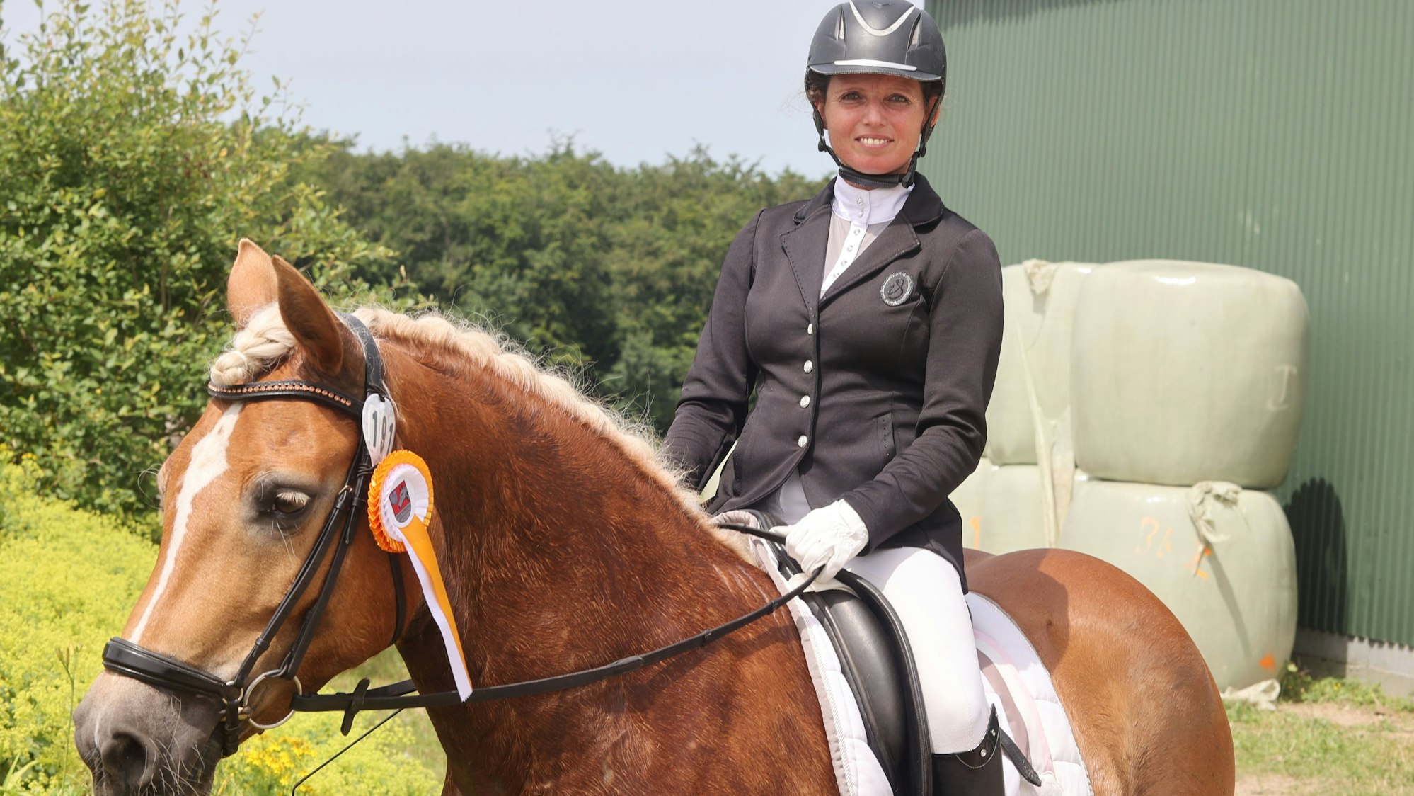 Eine Reiterin sitzt auf ihrem Pferd.