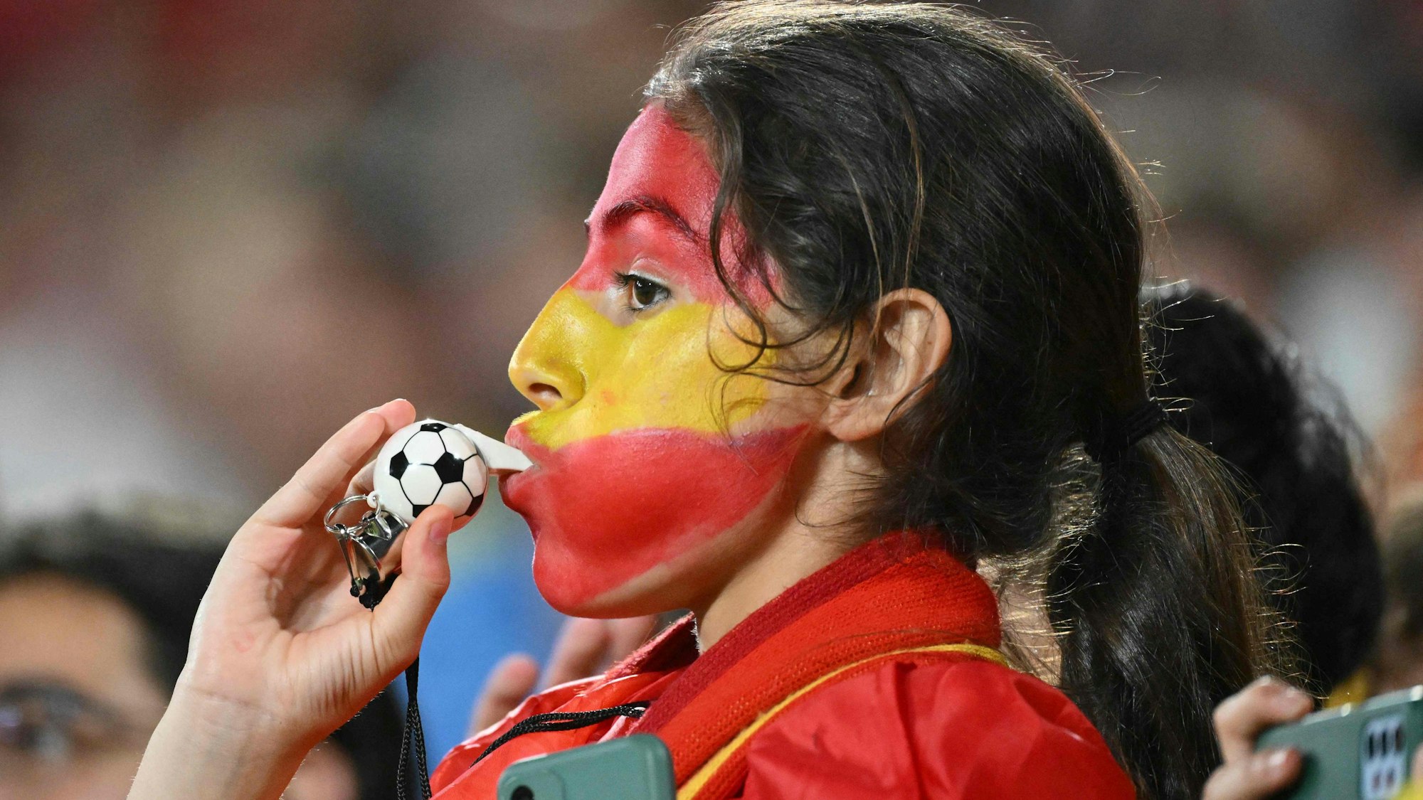 Spanischer weiblicher Fan mit Fußball-Trillerpfeife im Mund.