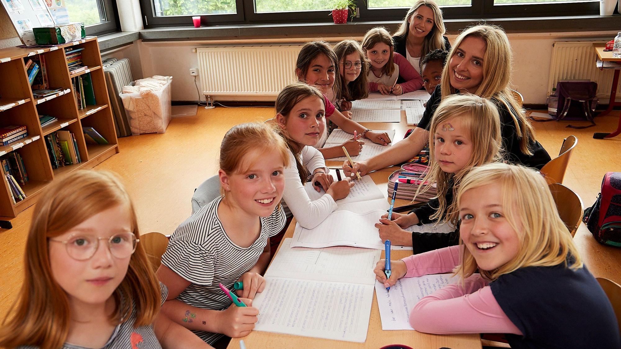 Schüler der Klasse 3a der Grundschule Reifferscheid sitzen mit ihrer Lehrerin und einer Teilnehmerin der Aktion Tagwerk an einem Tisch.