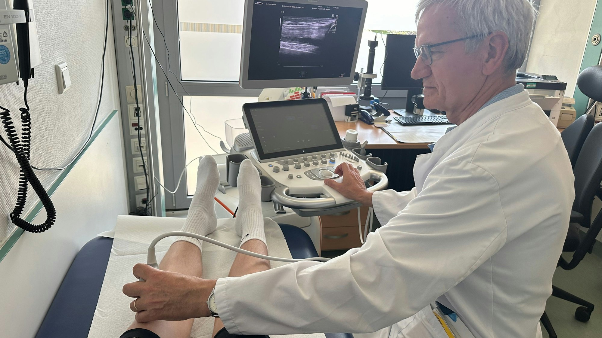 Professor Horneff, ärztlicher Leiter der Kinderklinik, untersucht ein Kniegelenk bei einem Jugendlichen