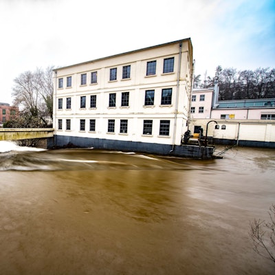 Das Foto zeigt das Alte Turbinenhaus und das Wehr bei Hochwasser.
