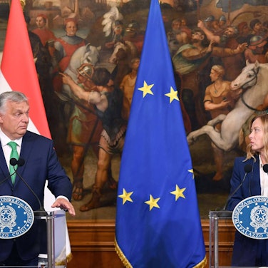 Orban und Meloni stehen an Pulten, sie haben Flaggen ihrer Länder im Hintergrund. Zwischen ihnen hängt die europäische Fahne.