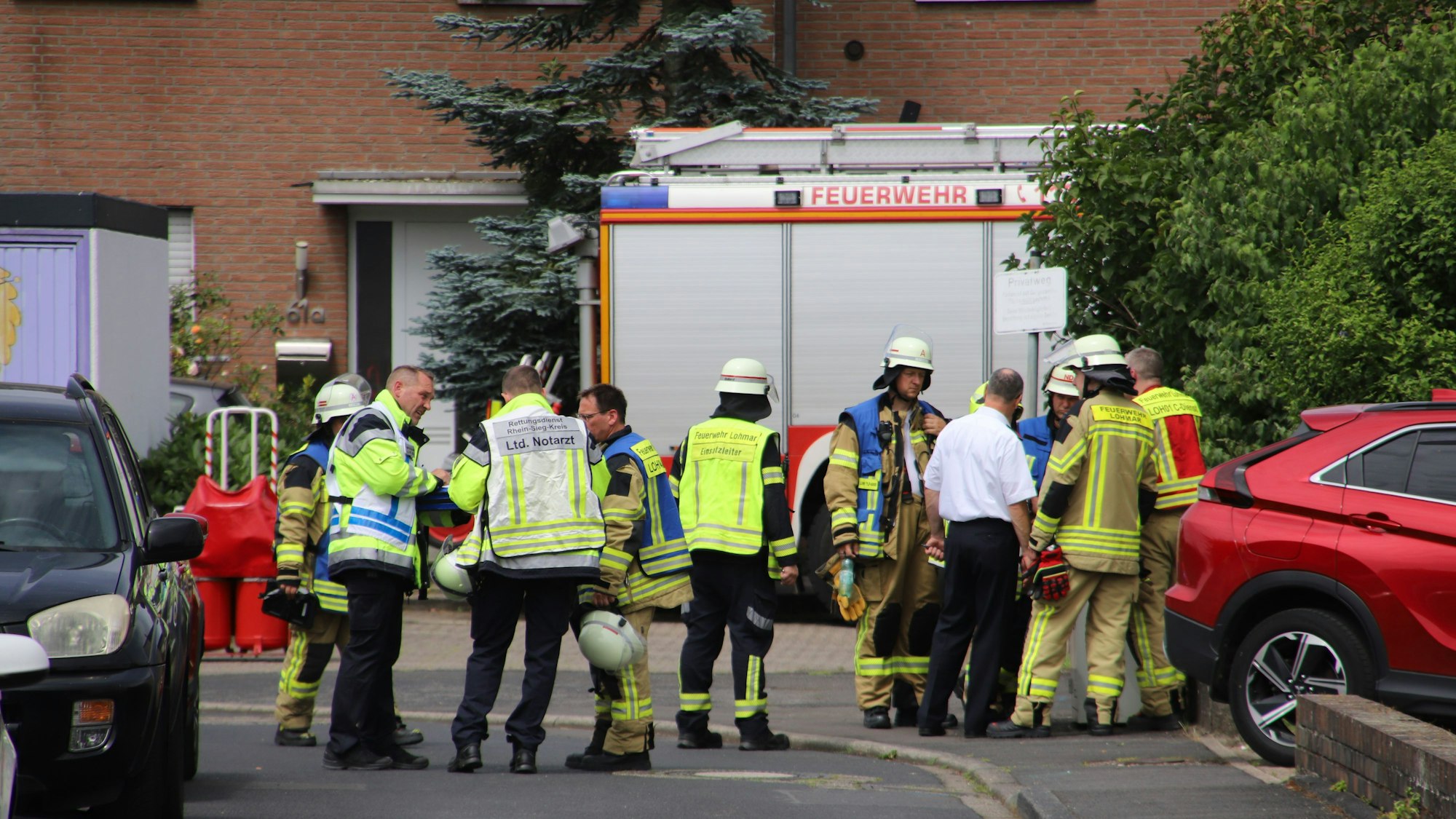 Mehrere Einsatzkräfte der Feuerwehr stehen in einer Wohnstraße.