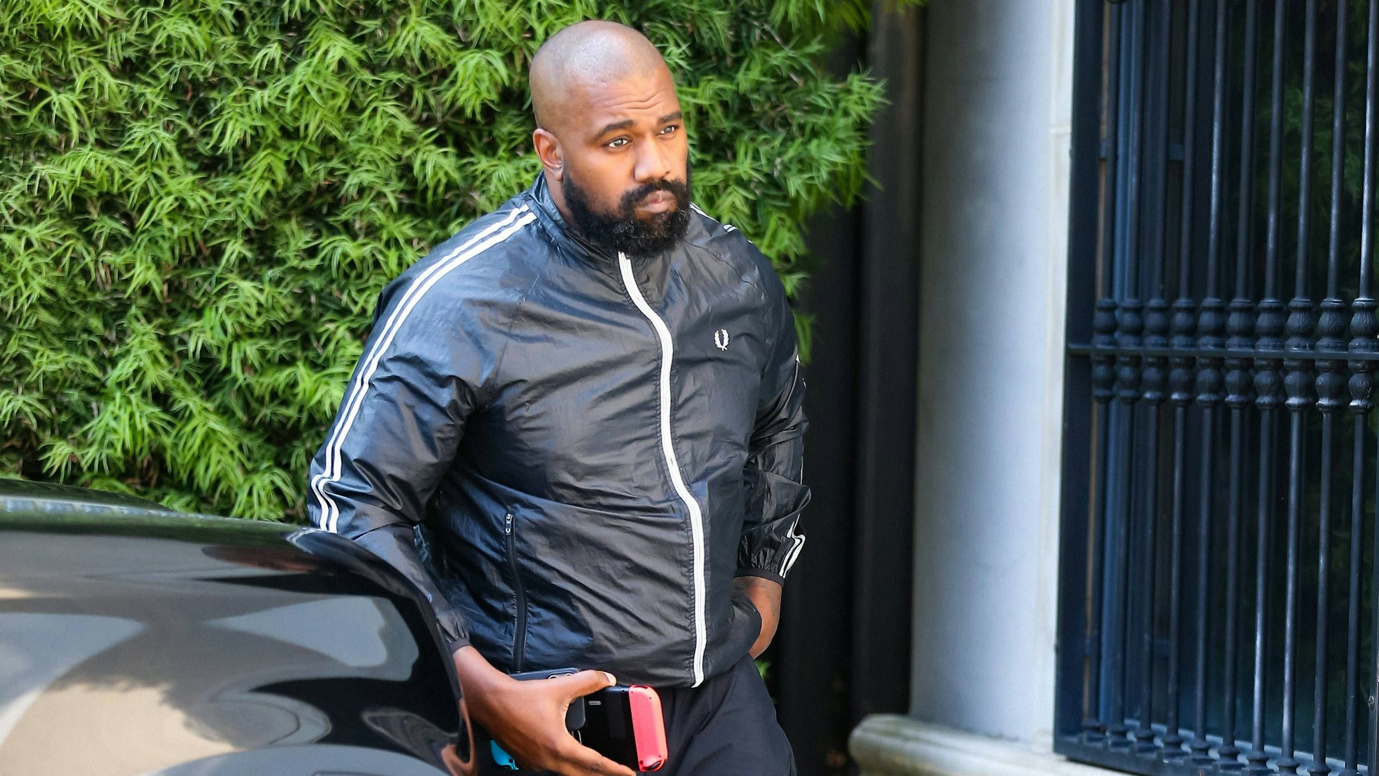 Kanye West geht an einem schwarzen Auto vorbei.