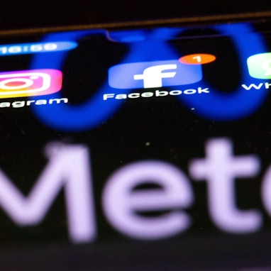 Die Apps Instagram, Facebook und WhatsApp sind auf dem Display eines Smartphones zu sehen, indem sich das Logo des Internetkonzerns Meta spiegelt. (Symbolbild)