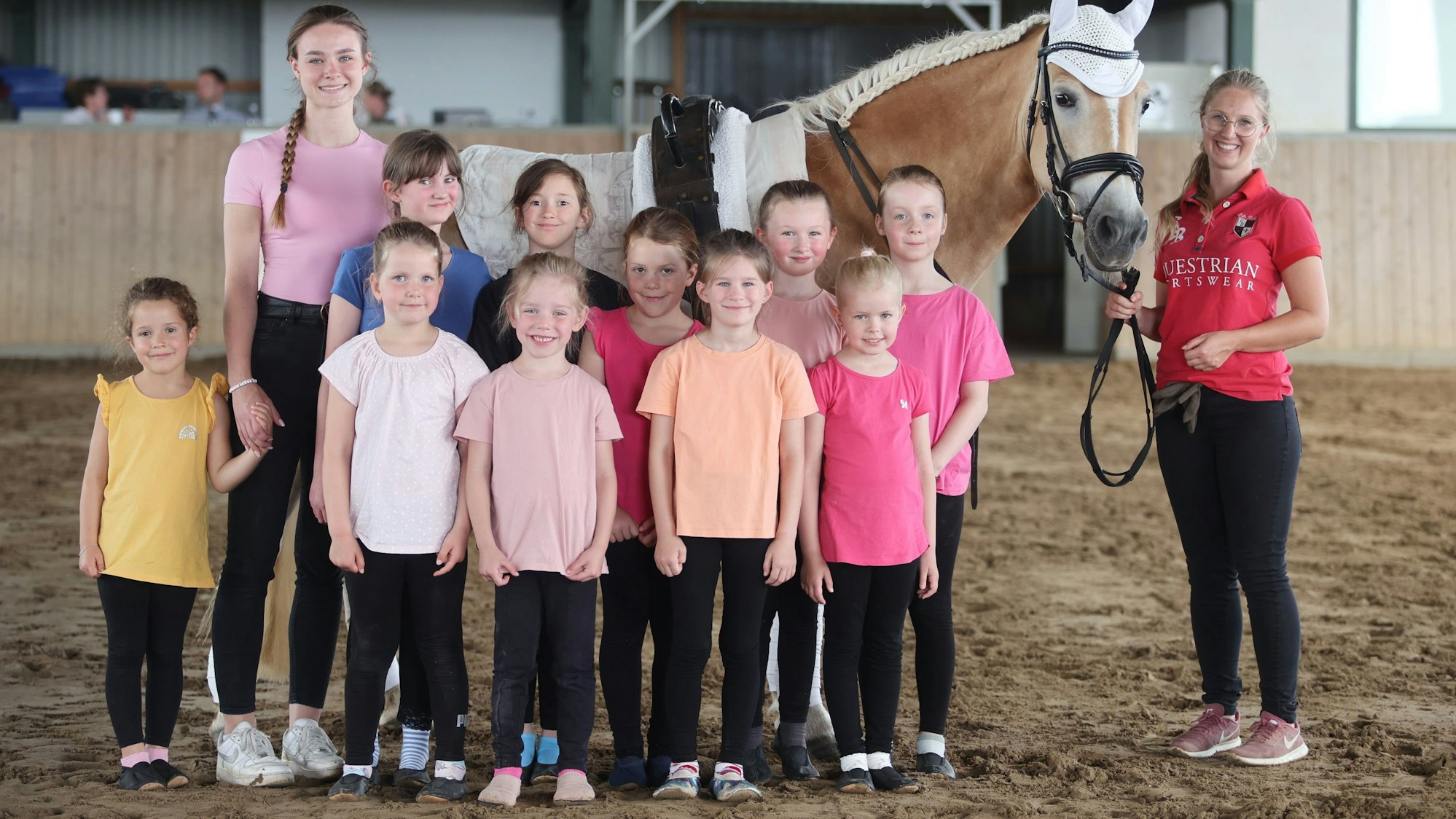 Zu sehen sind zwei Erwachsene und zehn Kinder vor einem Pferd.