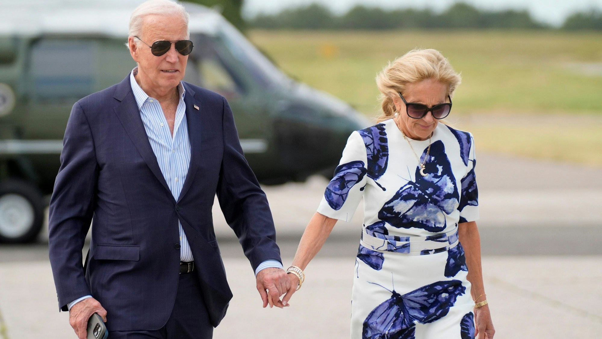 US-Präsident Joe Biden und First Lady Jill Biden halten Händchen am Flughafen.