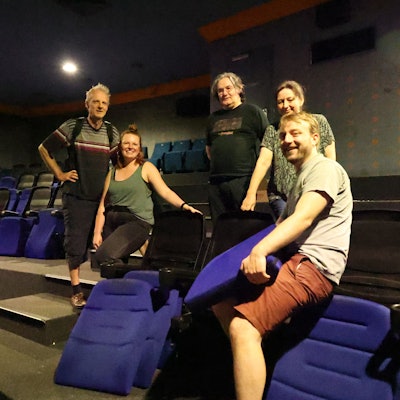 Männer und Frauen tragen Kinosessel weg.