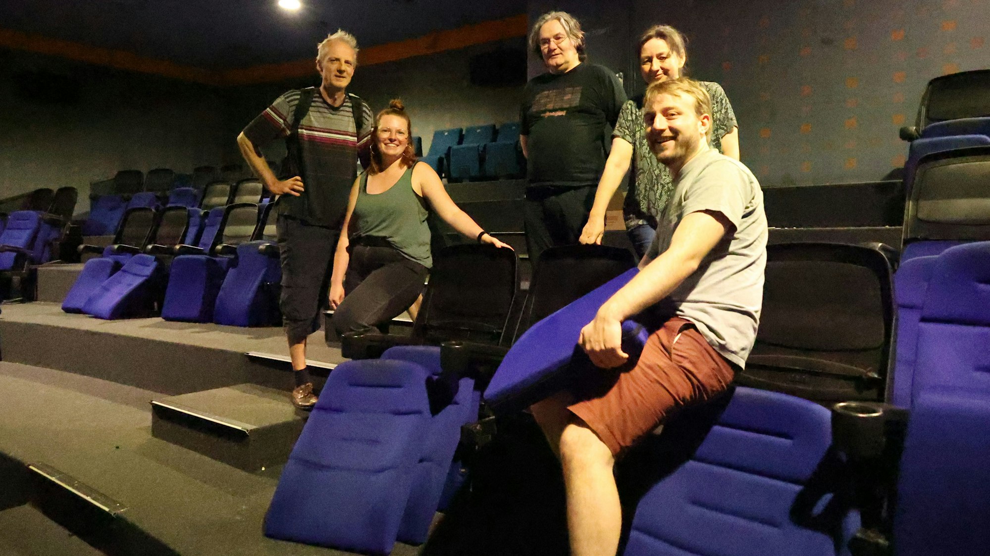 Männer und Frauen tragen Kinosessel weg.