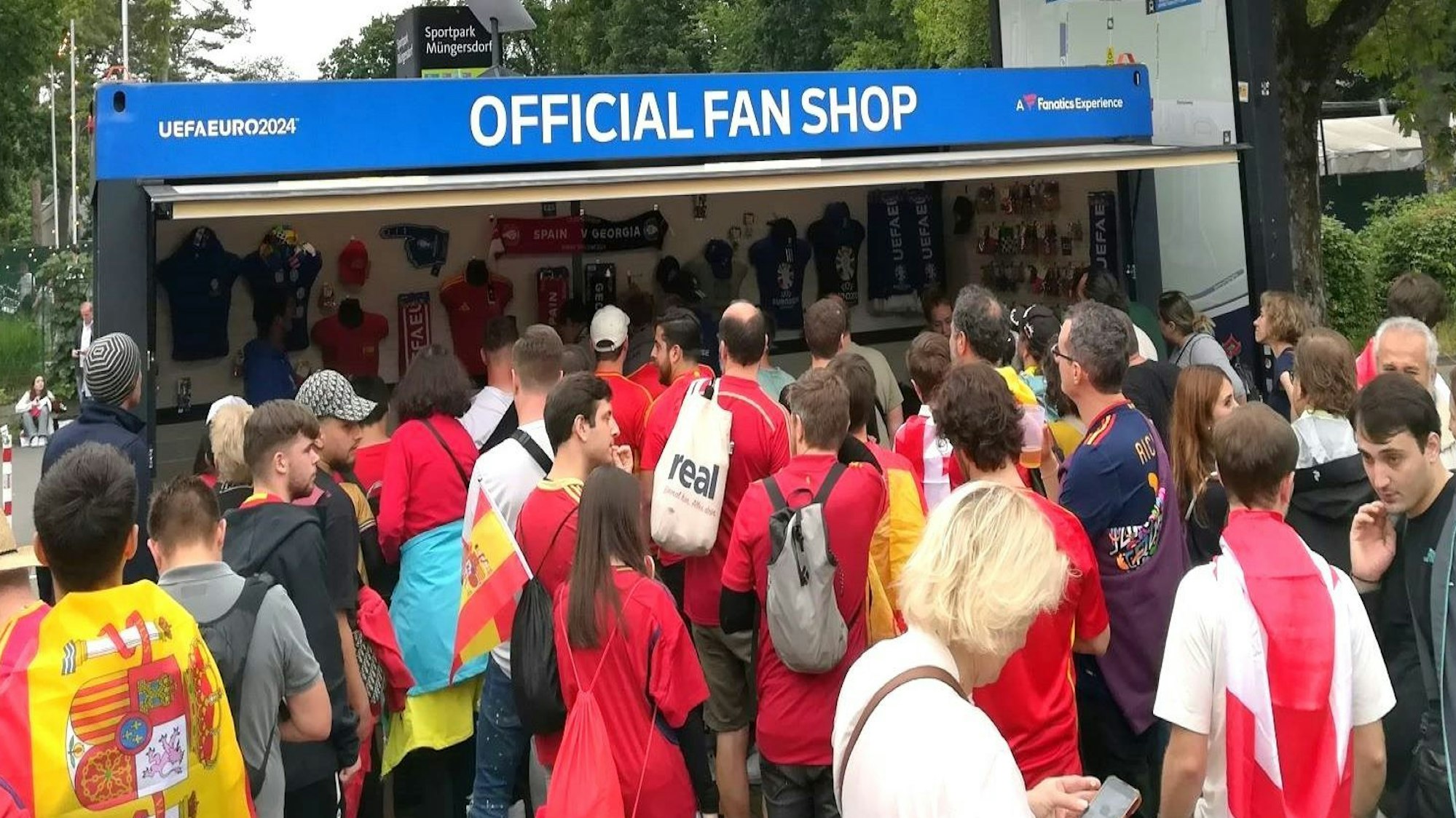 Zu sehen sind Fußballfans, die an einem offiziellen Uefa-Fanshop am Rhein-Energie-Stadion anstehen.