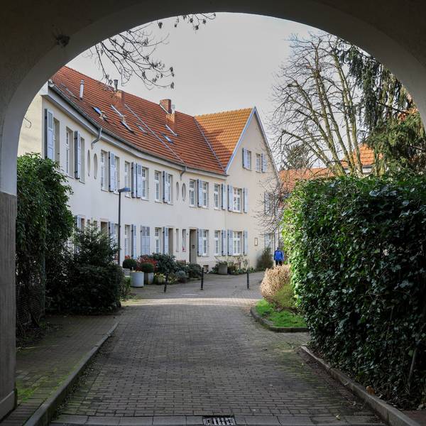 Zu sehen ist eine Häuserzeile durch einen Torbogen hindurch.
