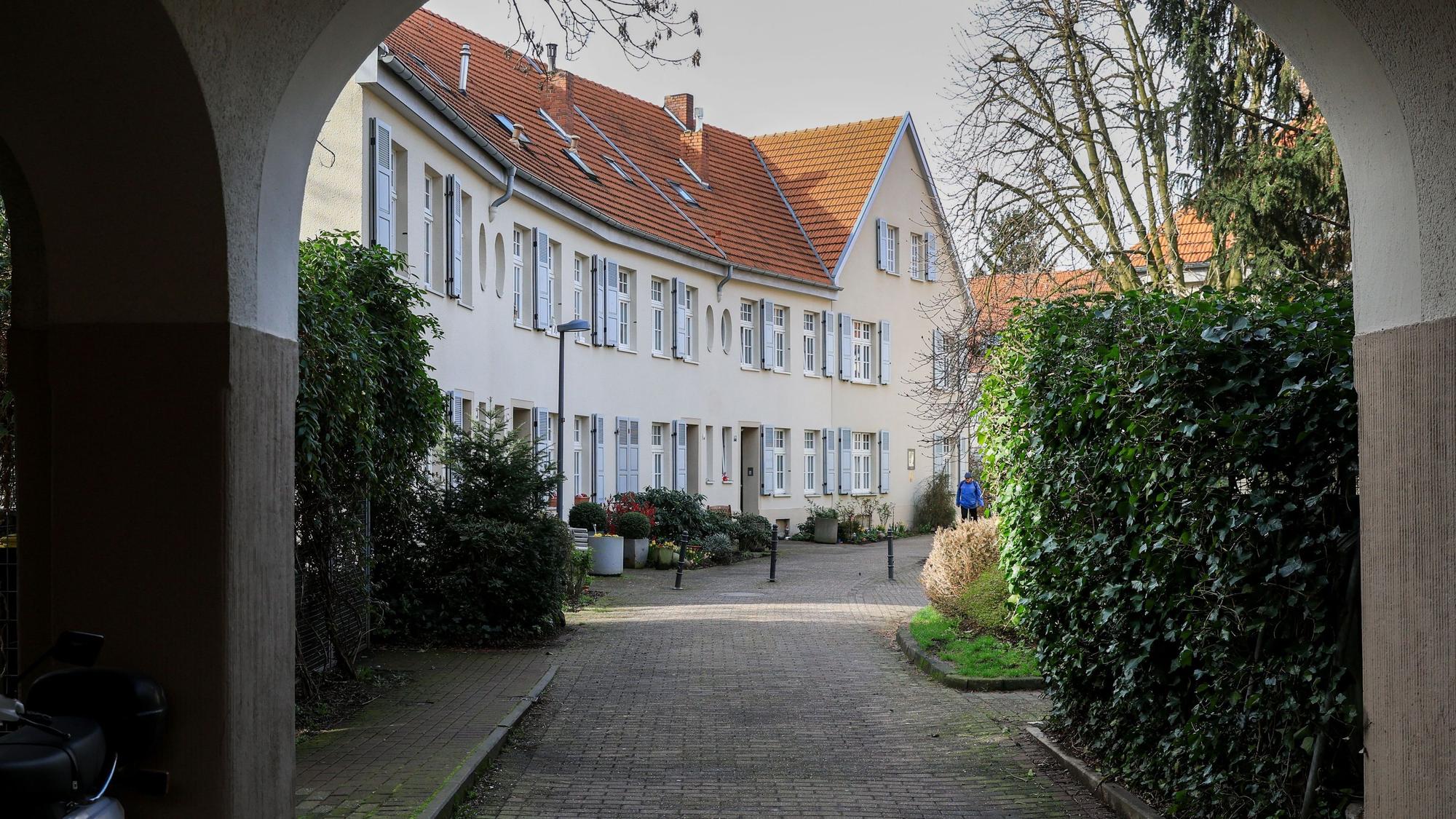 Zu sehen ist eine Häuserzeile durch einen Torbogen hindurch.