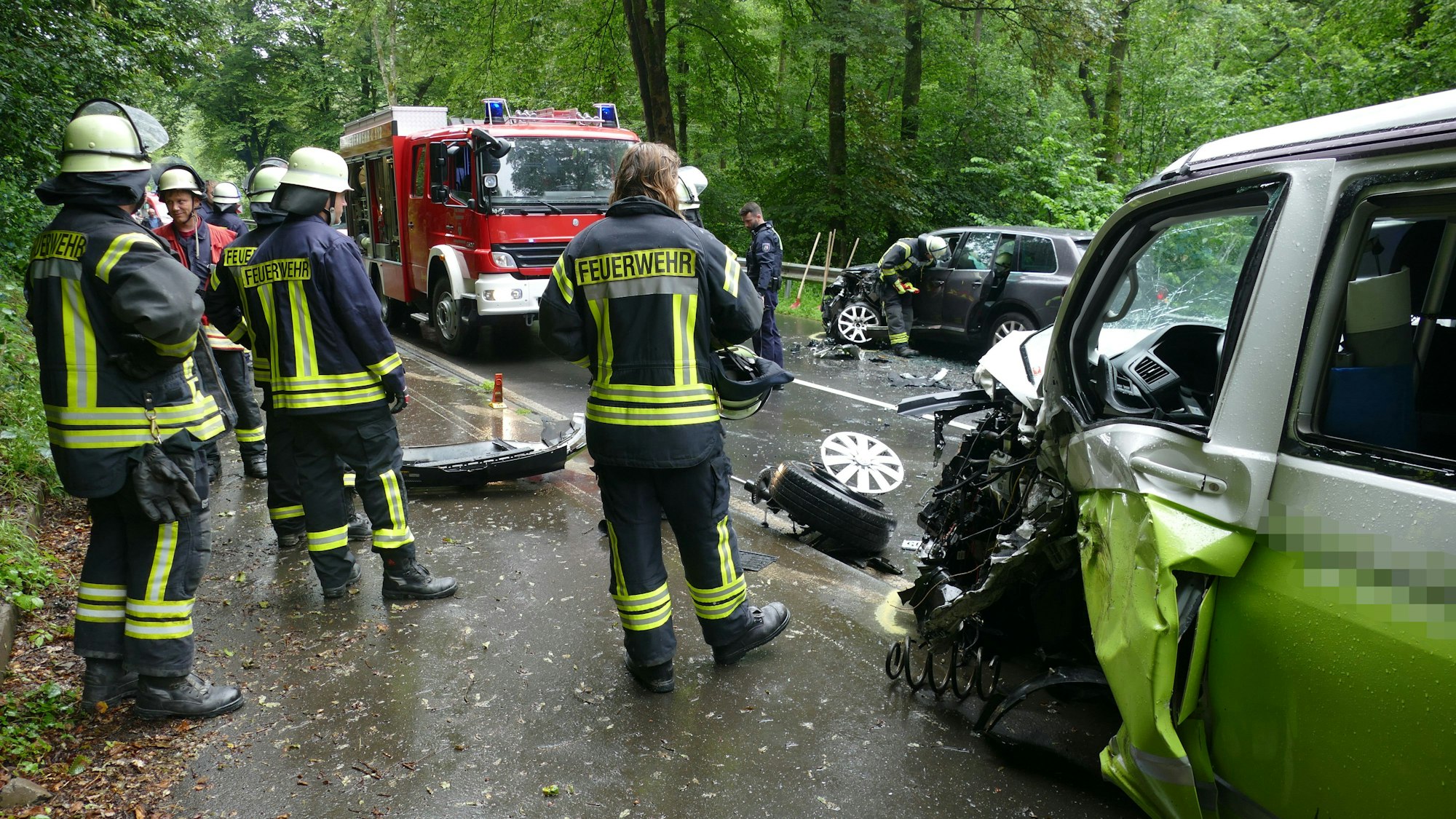 Feuerwehrleute stehen zwischen zwei beschädigten Autos.