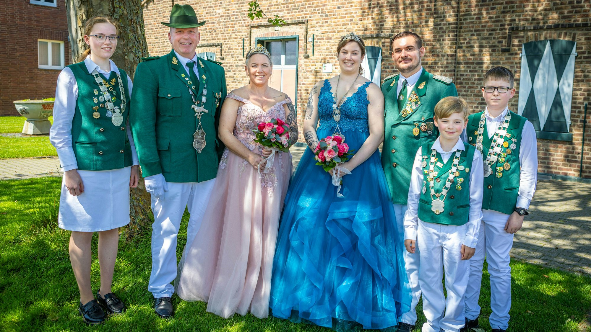 Männer und Frauen in Kleidern und Uniform lächeln.
