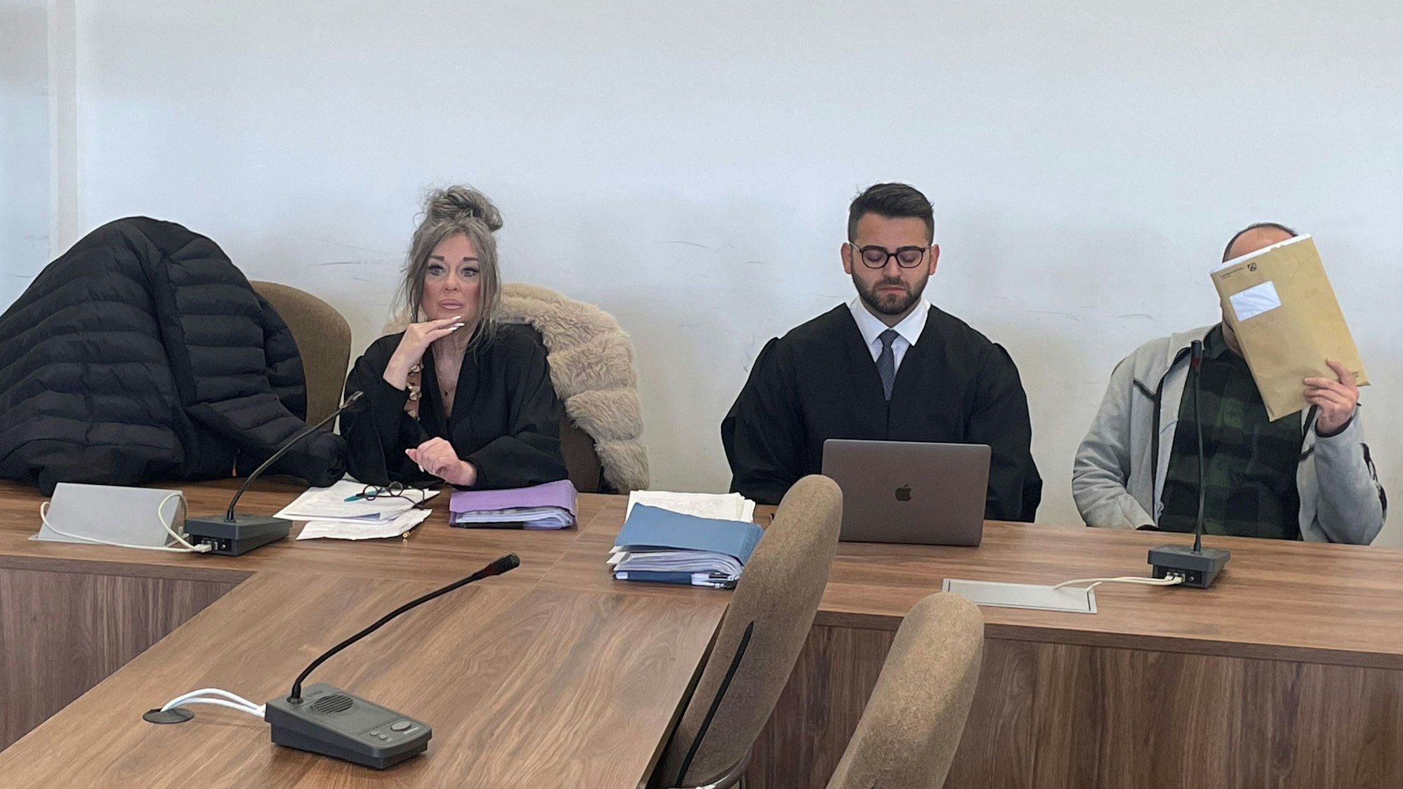Die Angeklagten, dazwischen ihre Verteidiger Petra Wunsch und Salih Kocak, verstecken sich beim Prozessauftakt hinter einer Jacke und einer Mappe vor den Pressefotografen.