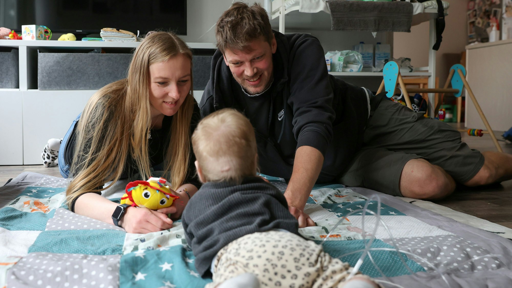 Sandra und Jens Leuschen spielen mit ihrer jüngsten Tochter Lucy auf einer Babydecke.